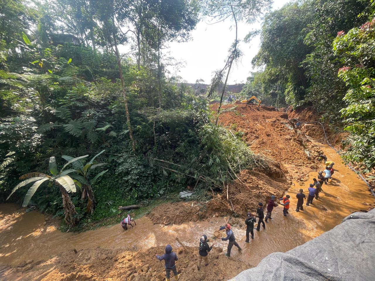 Warga bersama petugas Perumda Tirta Pakuan Kota Bogor membersihkan material longsor yang memutus akses jalan  di Desa Tangkil, Kecamatan Caringin, Kabupaten Bogor.