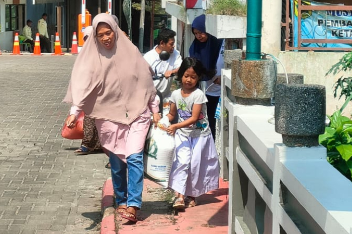 Warga Desa Semplak Barat membawa beras Bansos, Jumat (7/6/2024).
