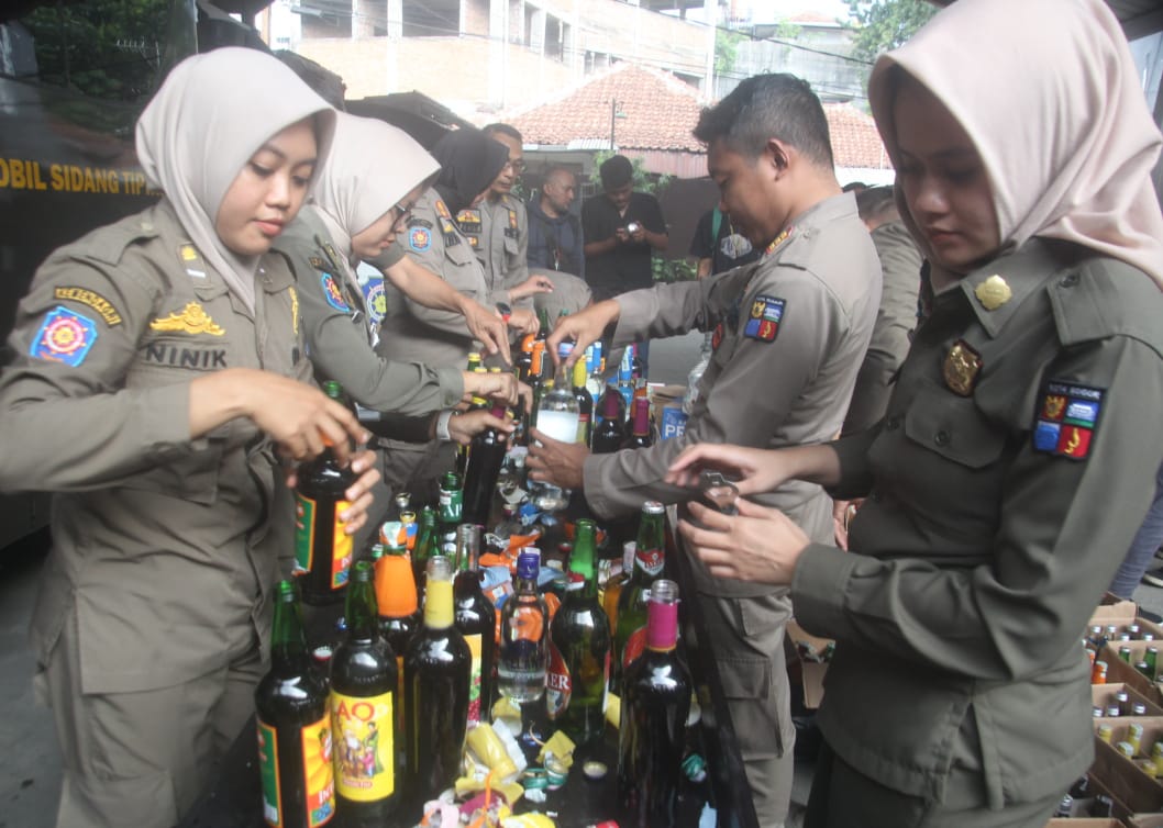 Petugas Satpol PP Kota Bogor, memusnahkan ribuan botol miras hasil razia di kantornya, Senin (8/7/2024).