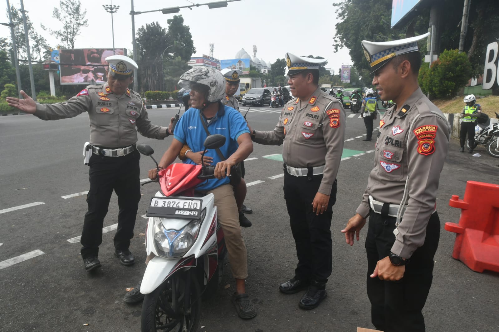 Petugas Polresta Bogor Kota bagi-bagi helm gratis kepada sejumlah warga yang terjaring Operasi Patuh Lodaya 2024, Jumat (19/7/2024).