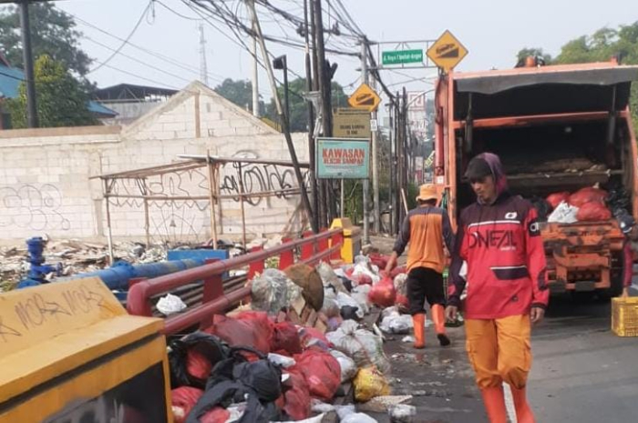 Ilustrasi petugas kebersihan mengangkut sampah liar di wilayah Parung. Kepala UPT membantah uang tunjangan kesehatan PHL belum dibayarkan.