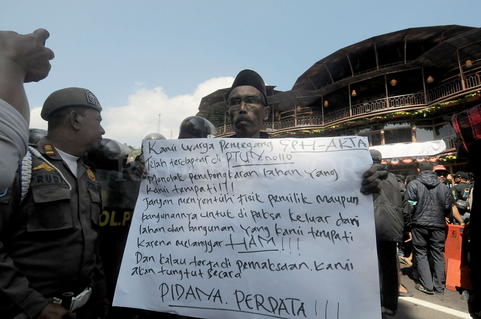 Warga menunjukan poster  saat dilakukan pembongkaran 196 bangunan di Puncak, Cisarua. Foto :