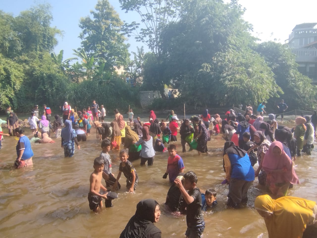Ribuan warga Kelurahan Sukahati, Kecamatan Cibinong, Kabupaten Bogor, saat mengikuti pesta rakyat menangkap ikan di Sungai Ciliwung, Minggu (1/9/2024).
