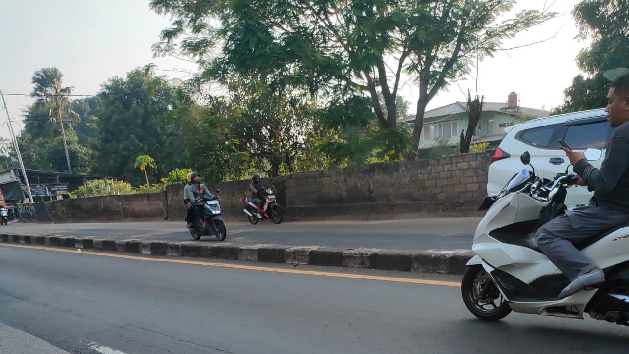 Salah satu pengendara menggunakan hp saat berkendara di Jalan Raya Parung Bogor, kamis sore (17/10/2024).