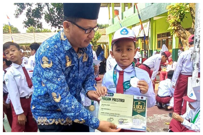 Kepala SDN Sukadamai 3, Akhmad Askolani menyerahkan medali yang diraih siswanya dalam perhelatan pencak silat UCS 2024 2024.
