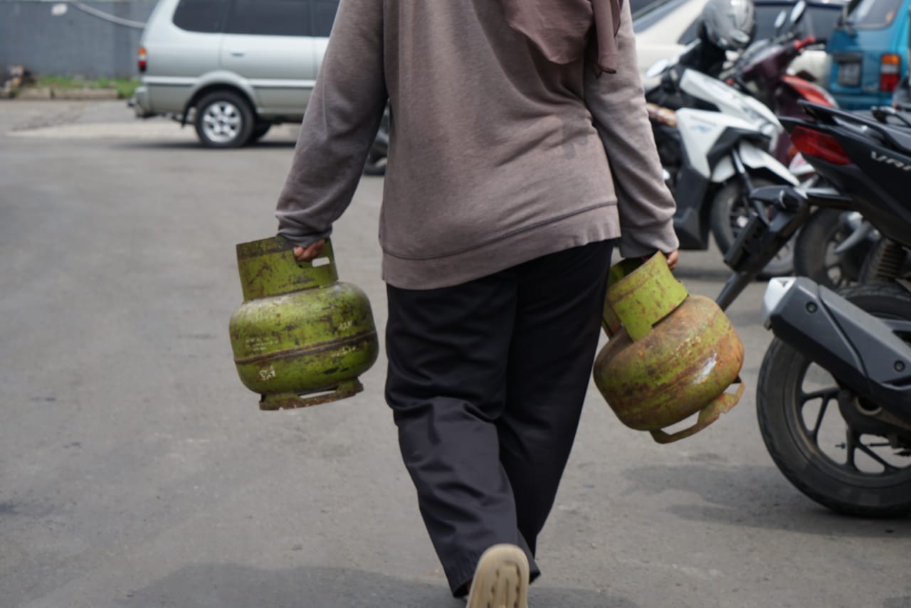 Seorang warga membawa dua tabung gas elpiji 3 kg.