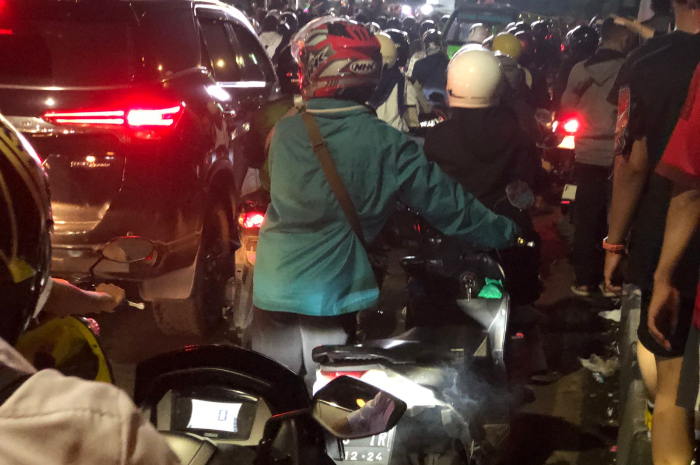 Pengendara mendorong motor karena mogok saat terjadi kemacetan di Jalan Otista Bogor, Rabu (12/2/2025) malam.