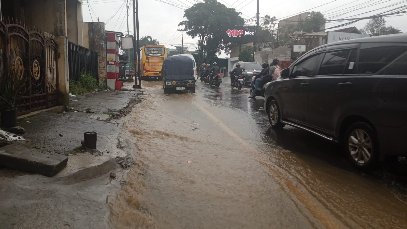 Air dari saluran drainase di Jalan Raya Puncak, Gadog, Megamendung meluap hingga ke badan jalan setelah dilanda hujan deras.
