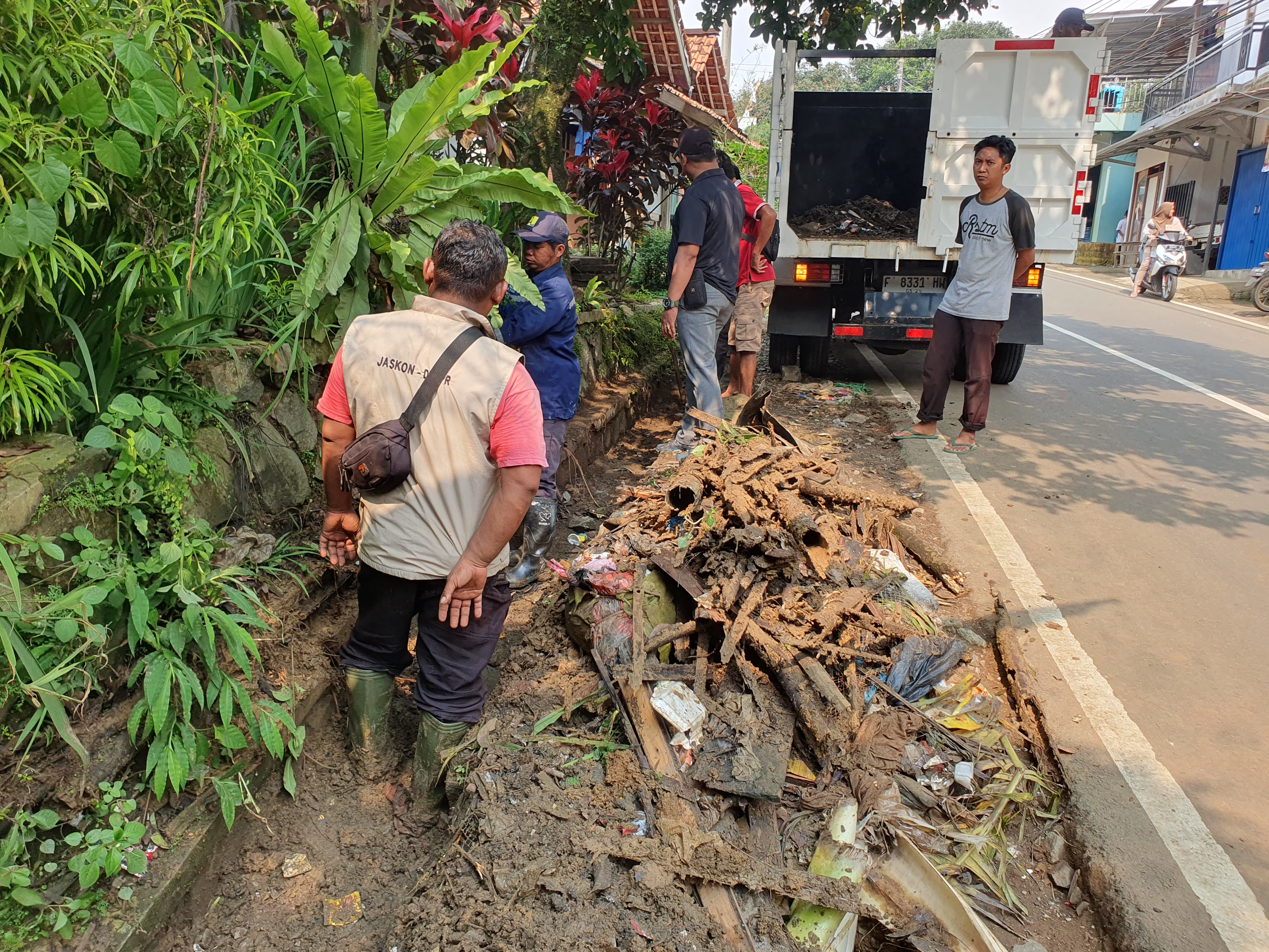Petugas membersihkan saluran air yang sebabkan banjir di jalan menuju kediaman Presiden Prabowo Subianto.