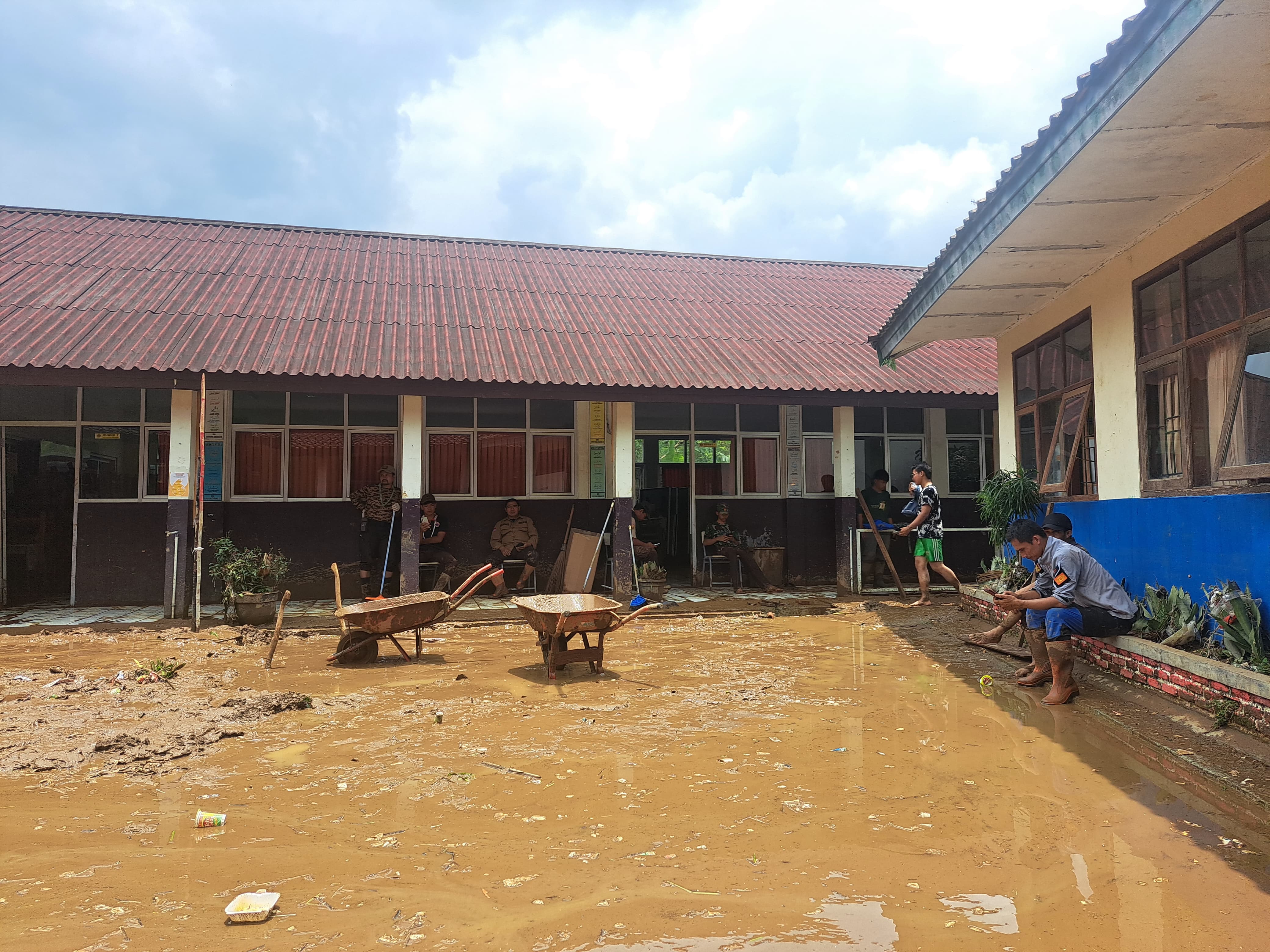 Guru-guru di SDN Cipayung Girang 2 dan 3 Megamendung sedang berupaya membersihkan lumpur pasca bencana banjir bandang pada Minggu (2/3/2025).