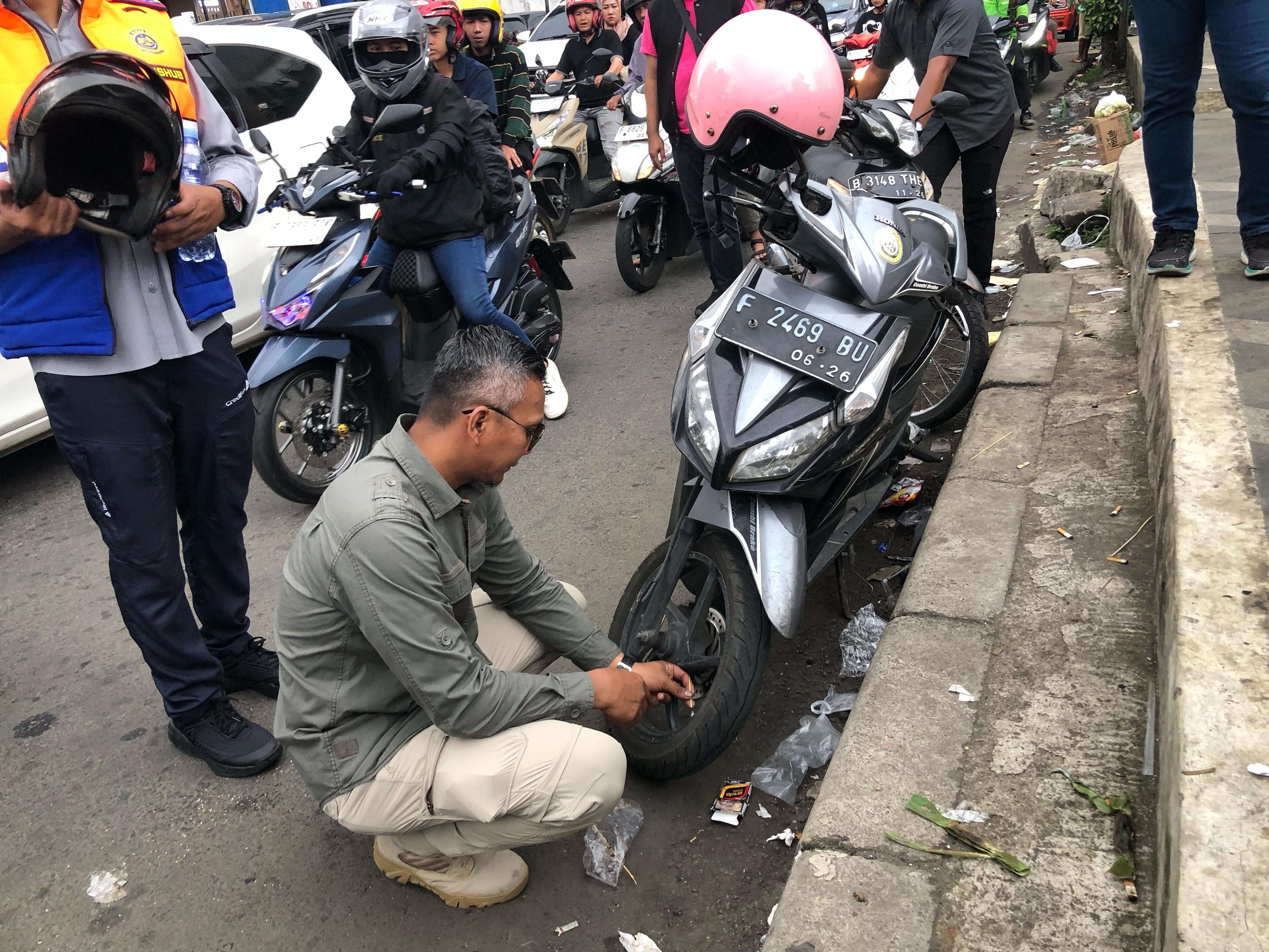 Wakil Wali Kota Bogor, Jenal Mutaqin, menggembosi ban motor yang parkir kendaraannya di Jalan Kapten Muslihat, Kamis (3/4/2025).