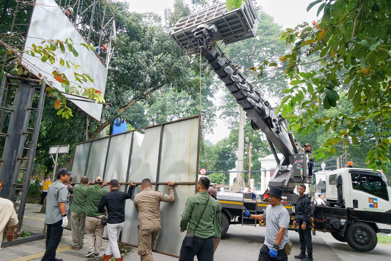 Sejumlah petugas Satpol PP Kota Bogor membongkar papan reklame di sepanjang Jalur Sistem Satu Arah (SSA) Rabu (9/4/2025).
