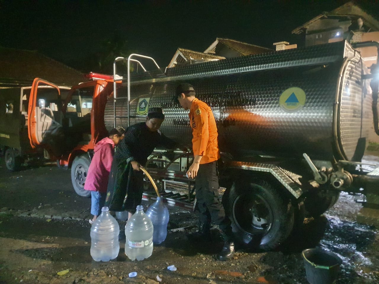 Petugas BPBD Kabupaten Bogor mendistribusikan bantuan air bersih kepada warga Kampung Jatinunggal, Desa Cipinang, Kecamatan Rumpin, Senin (5/5/2025) malam.