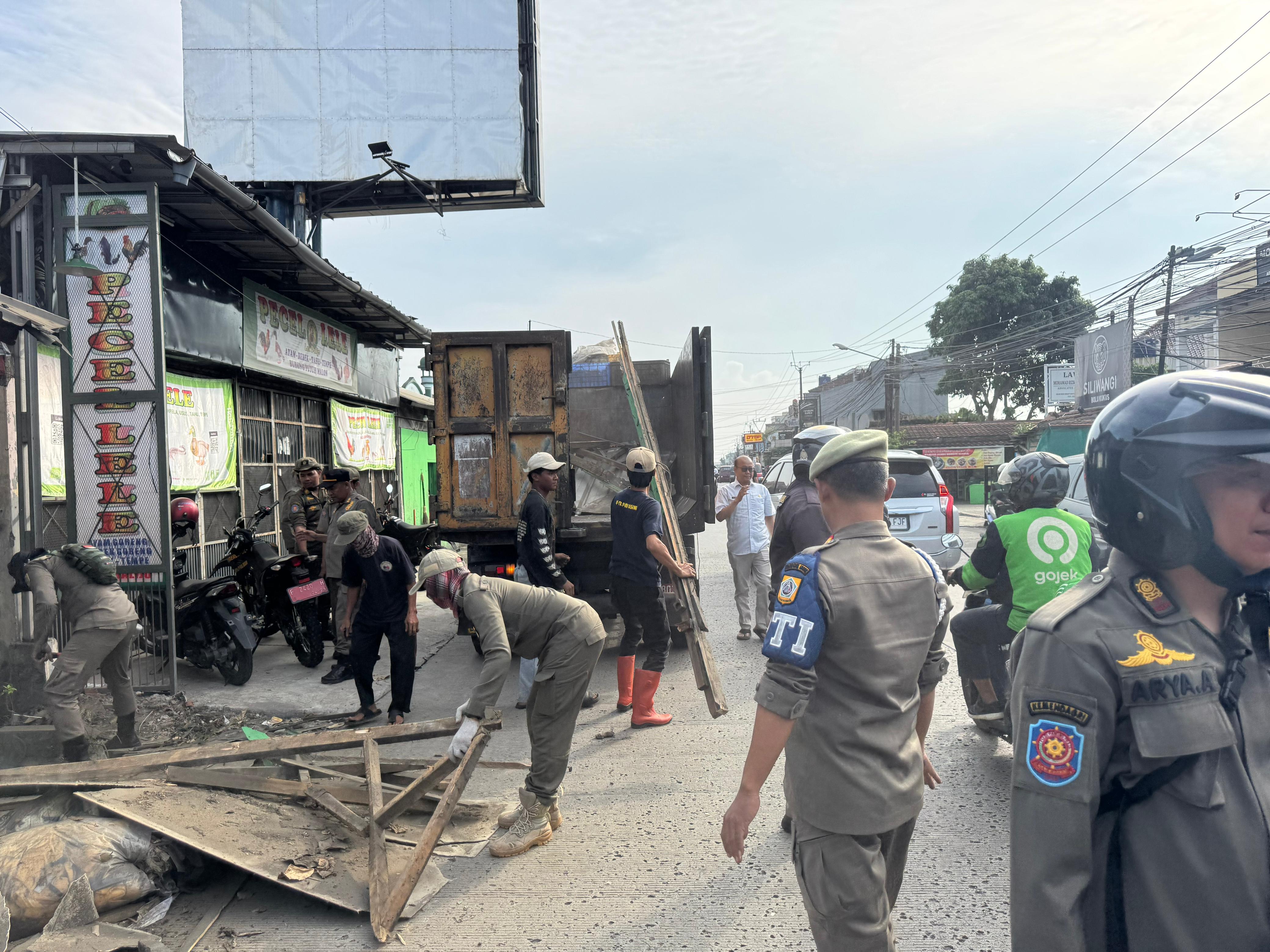 Petugas Satpol PP Kabupaten Bogor, membongkar bangunan liar di sepanjang Jalan Raya Sentul-Citeureup, Selasa (10/6/2025).