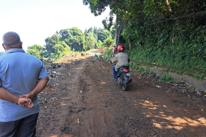 Salah seorang pengendara motor saat melintas di Jalan Saleh Danasasmita Batutulis yang masih penanganan akibat longsor Jumat 20 Juni 2025