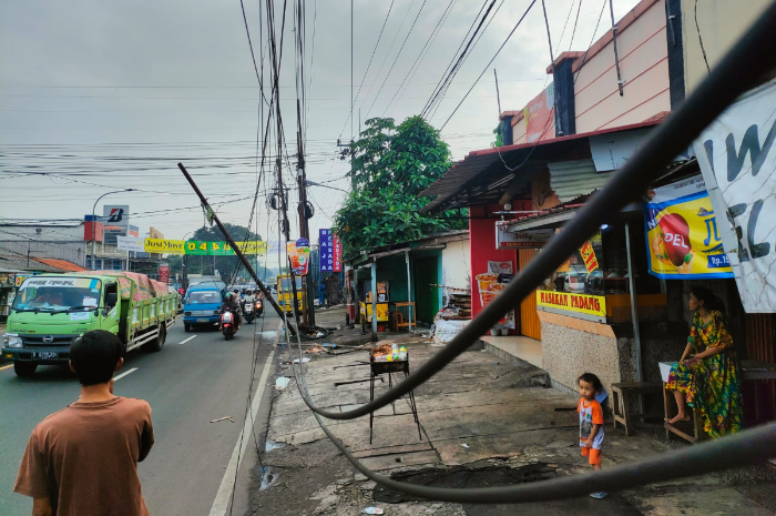 Kondisi tiang listrik di Jalan Raya Ciputat-Parung Kota Depok yang miring akibat kabel tersangkut dan tertarik kendaraan besar.
