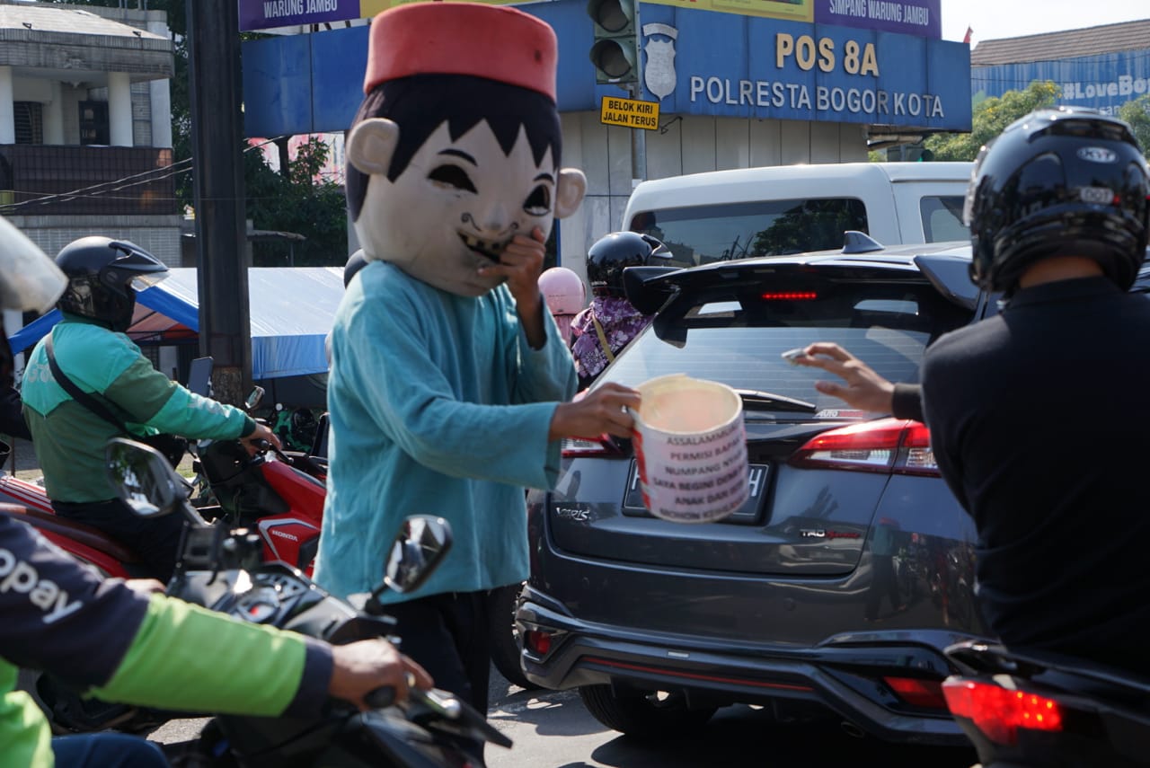 Pengamen badut sedang beraksi di simpangan jalan raya di Kota Bogor, Kamis 10 Juli 2025.