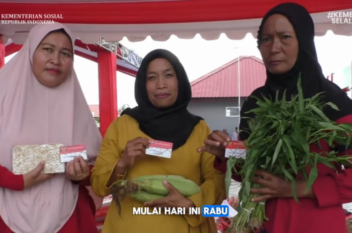 Ilustrasi penerima bansos yang sedang memegang kartu KKS merah putih
