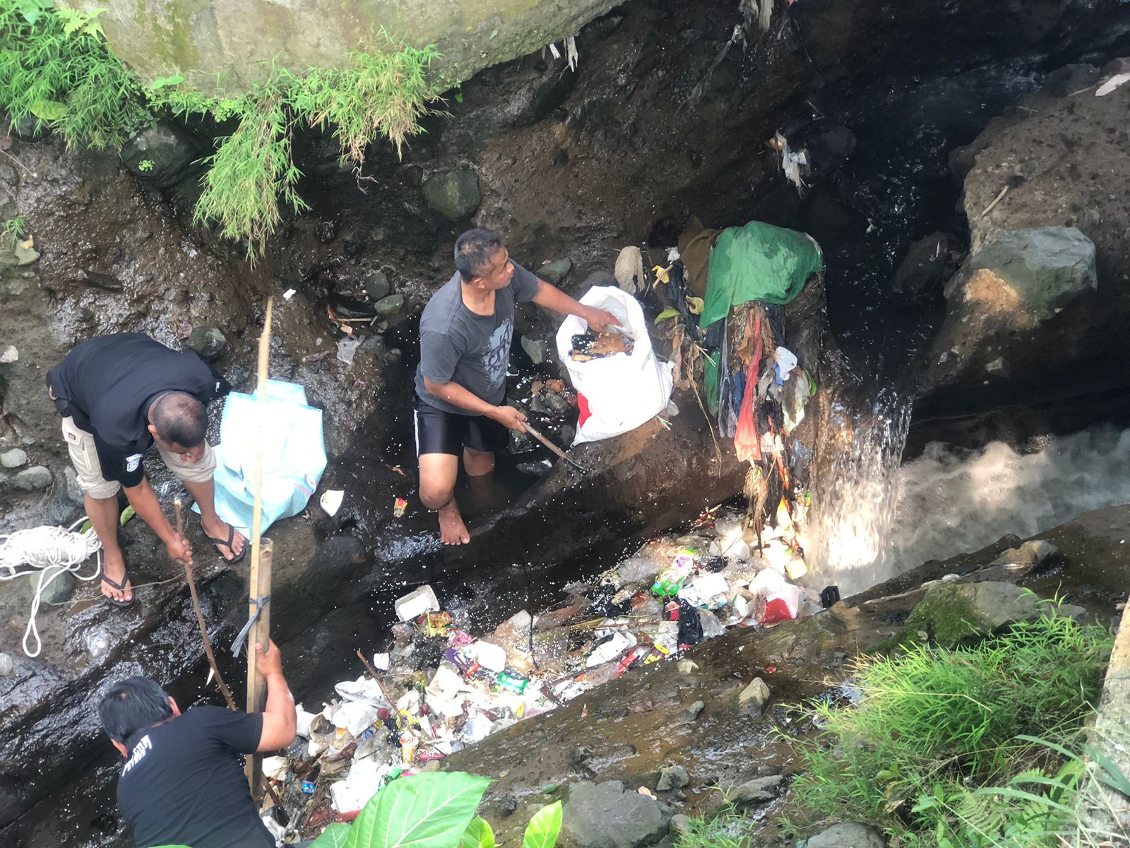 Warga membersihkan tumpukan sampah di aliran sungai depan Kantor Kecamatan Bogor Utara.