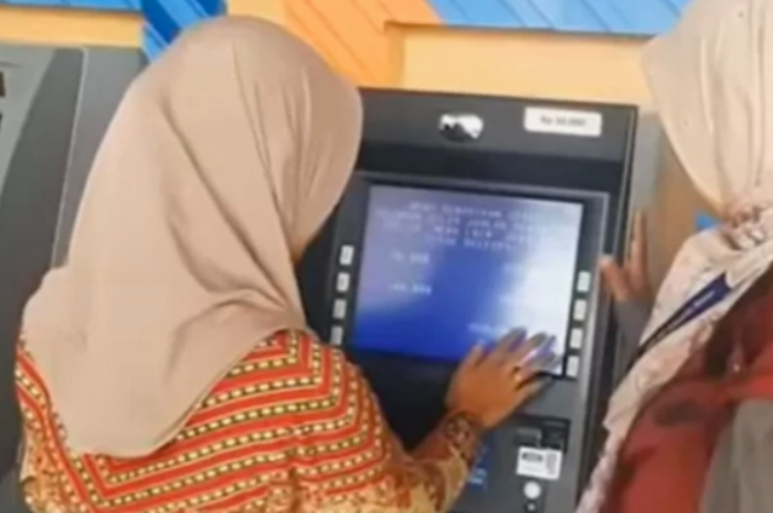 Penerima bansos saat mengecek saldo di ATM.