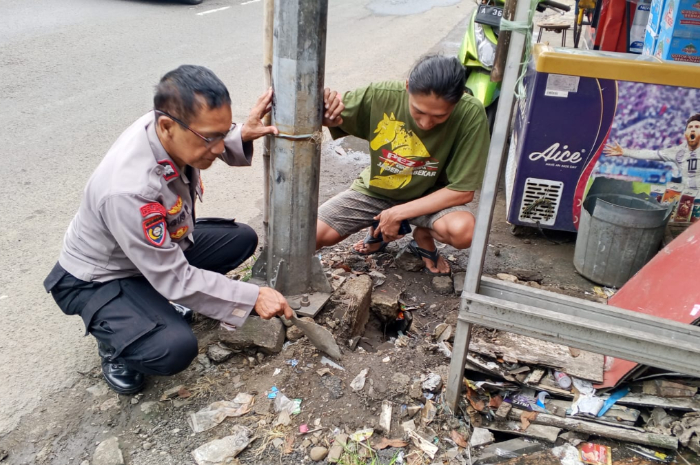 Petugas Polsek Cimanggis saat mengecek lokasi viral tanah mengeluarkan asap dan hawa panas di Jalan Raya Jakarta Bogor Selasa 11 Agustus 2025.