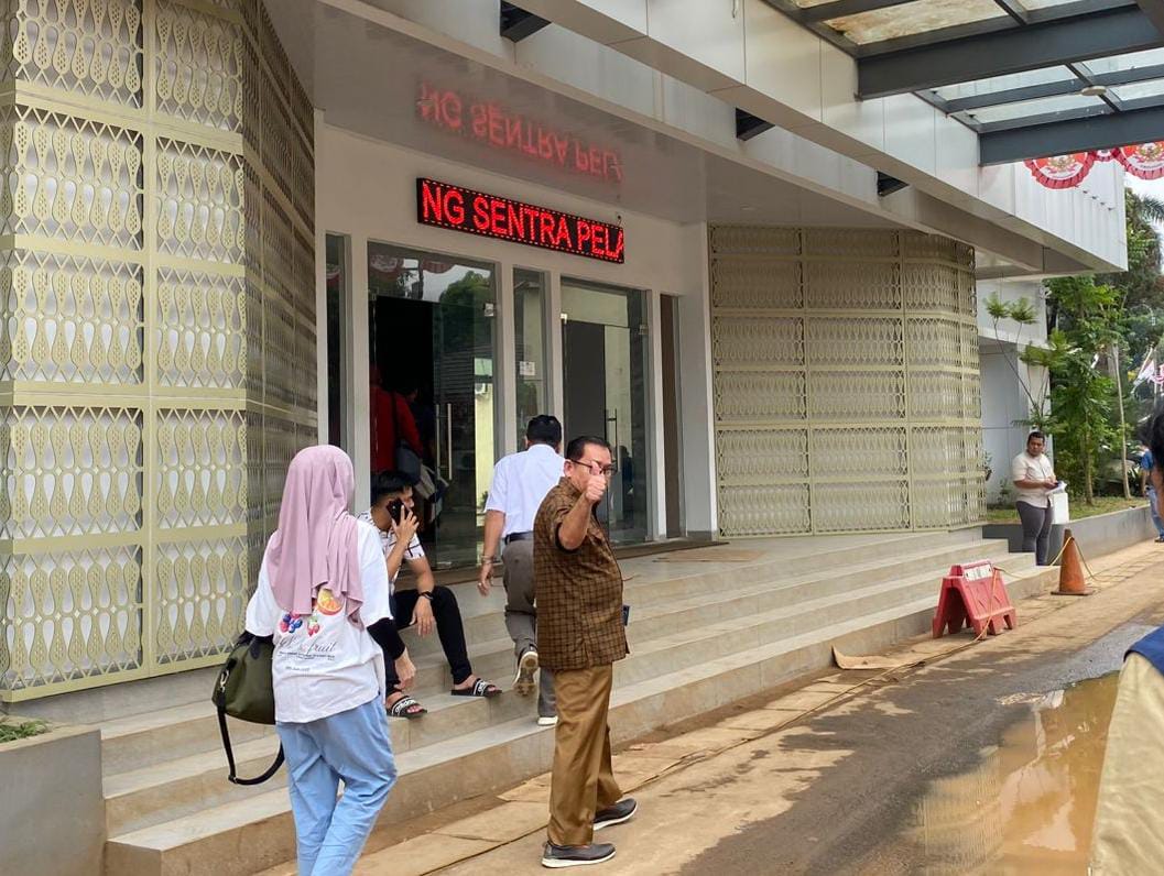 Kepala Desa Cikuda, AS menggunakan pakaian kemeja cokelat celana bahan saat memenuhi pemanggilan Polres Bogor untuk dilalukan pemeriksaan.