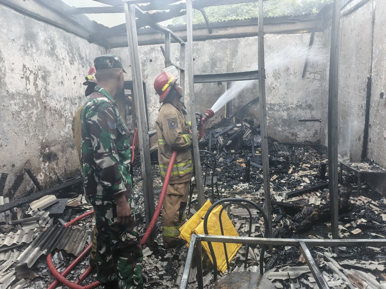 Petugas mendinginkan lokasi kios pecel lele di Desa Ciangsana, Kecamatan Gunung Putri, Kabupaten Bogor, yang ludes terbakar.
