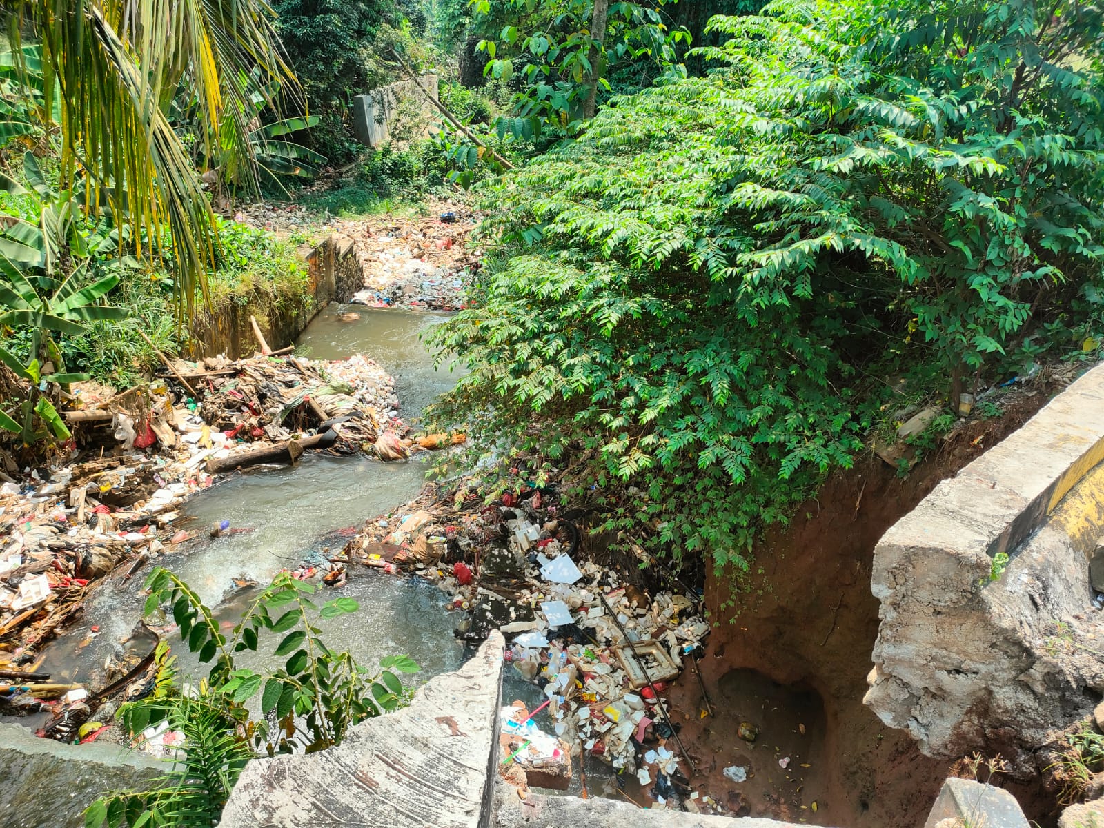 Penampakan tebing longsor dan tumpukan sampah di Kali Pesanggrahan Kota Depok
