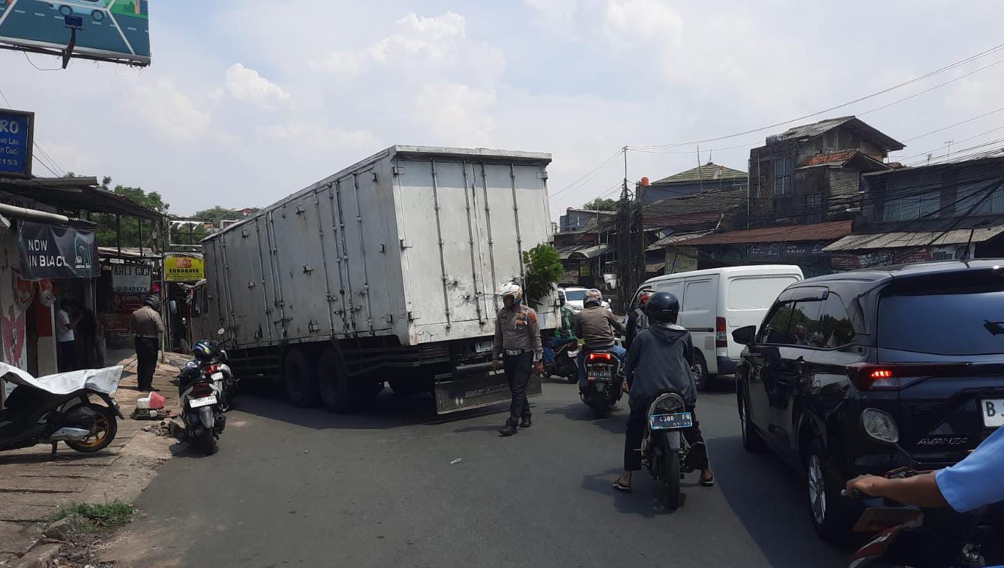 Satu unit kendaraan truck box terperosok di Jalan Mayor Oking Citeureup, Kabupaten Bogor, Selasa 7 Oktober 2025.
