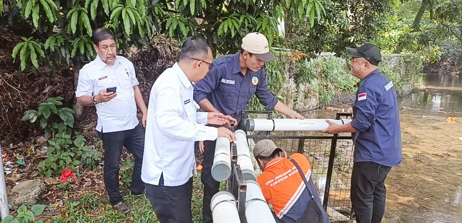 Petugas DLH Kabupaten Bogor saat memasang jaring apung disekitar saluran irigasi Situ Cikaret.