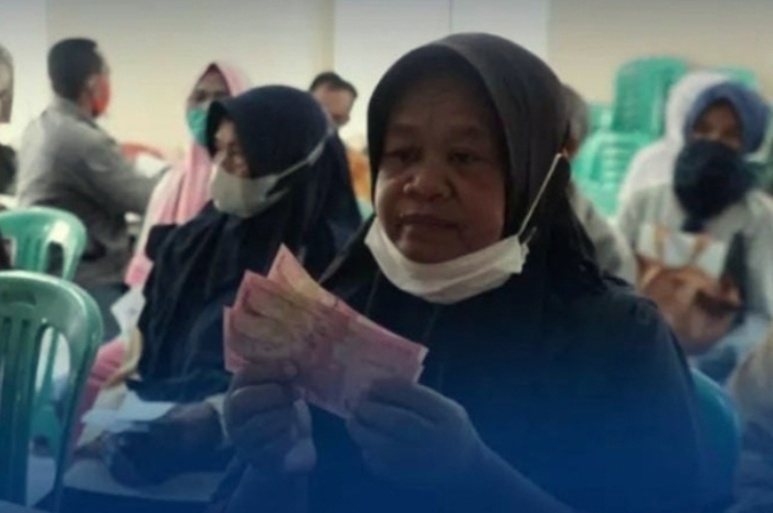 Penerima Bansos memperlihatkan uang yang diterimanya.