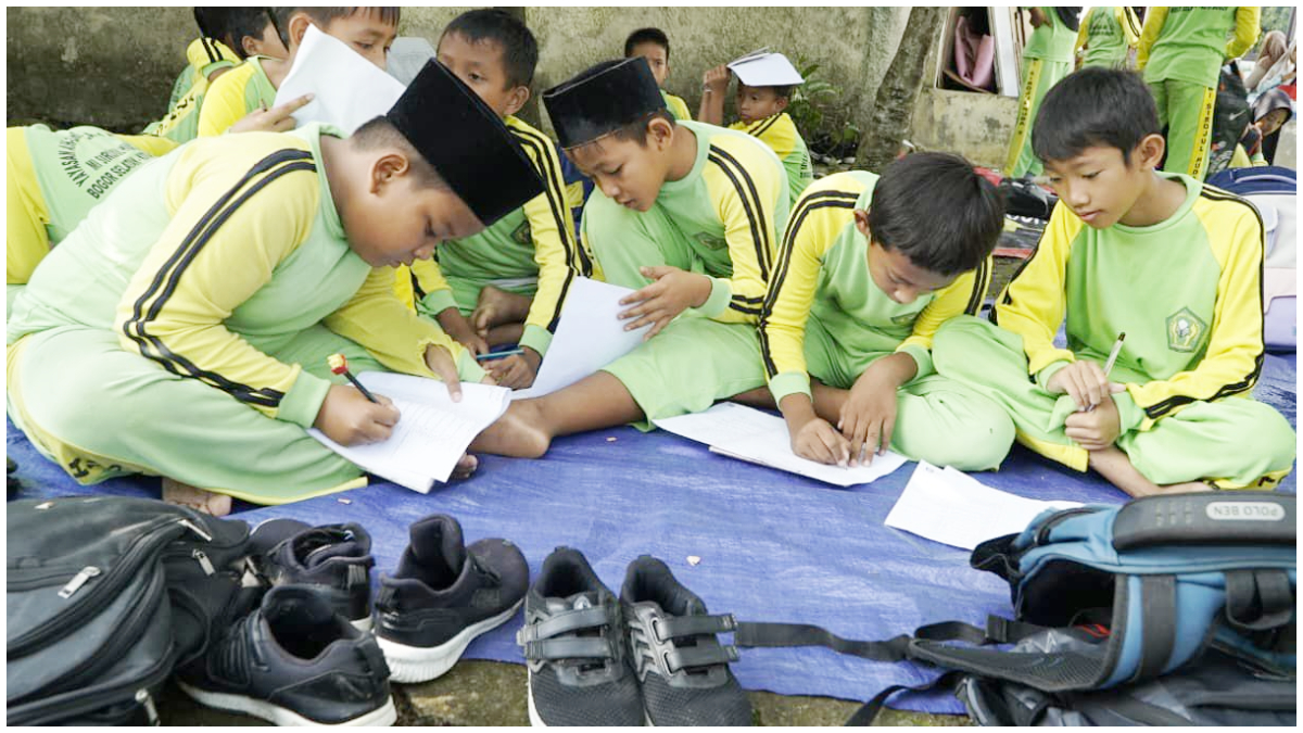 Siswa MI Sirojul Huda 2 yang tengah melaksanakan KBM di tanah.