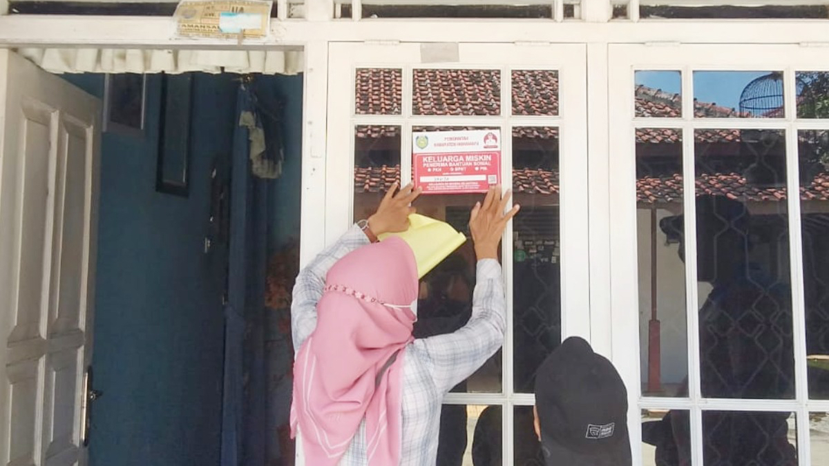 Ilustrasi pemasangan tanda rumah KPM Bansos PKH BPNT oleh pendamping sosial.