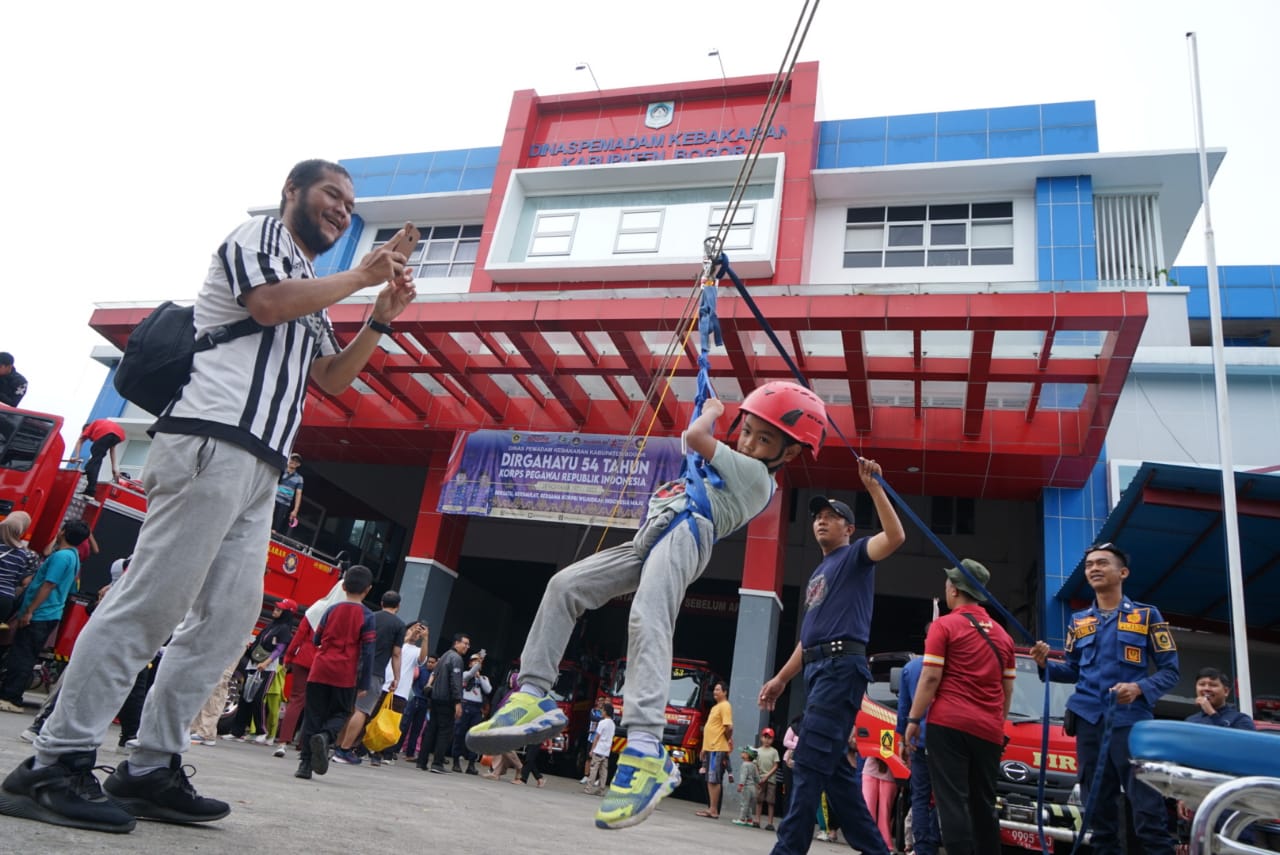 Seorang anak bermain flying fox dengan pengawasan anggota Damkar Kabupaten Bogor, sebagai sarana untuk menghibur saat Car Free Day (CFD) di Jalan Raya Tegar Beriman, Minggu 16 November 2025.