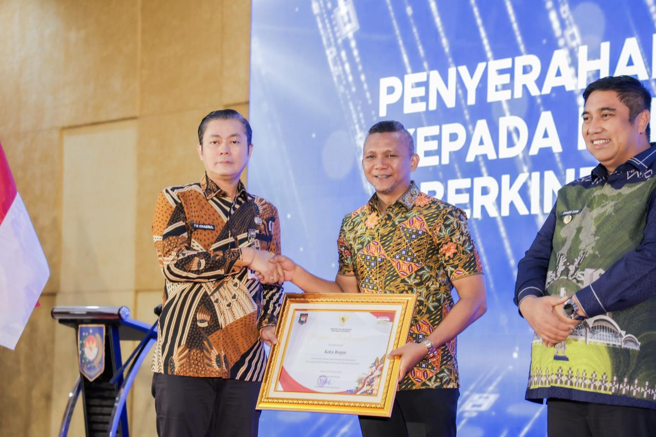 Direktur Sinkronisasi Urusan Pemerintahan Daerah III Kemendagri, Chaerul Dwi Sapta menyerahkan penghargaan kepada Wakil Wali Kota Bogor, Jenal Mutaqin.