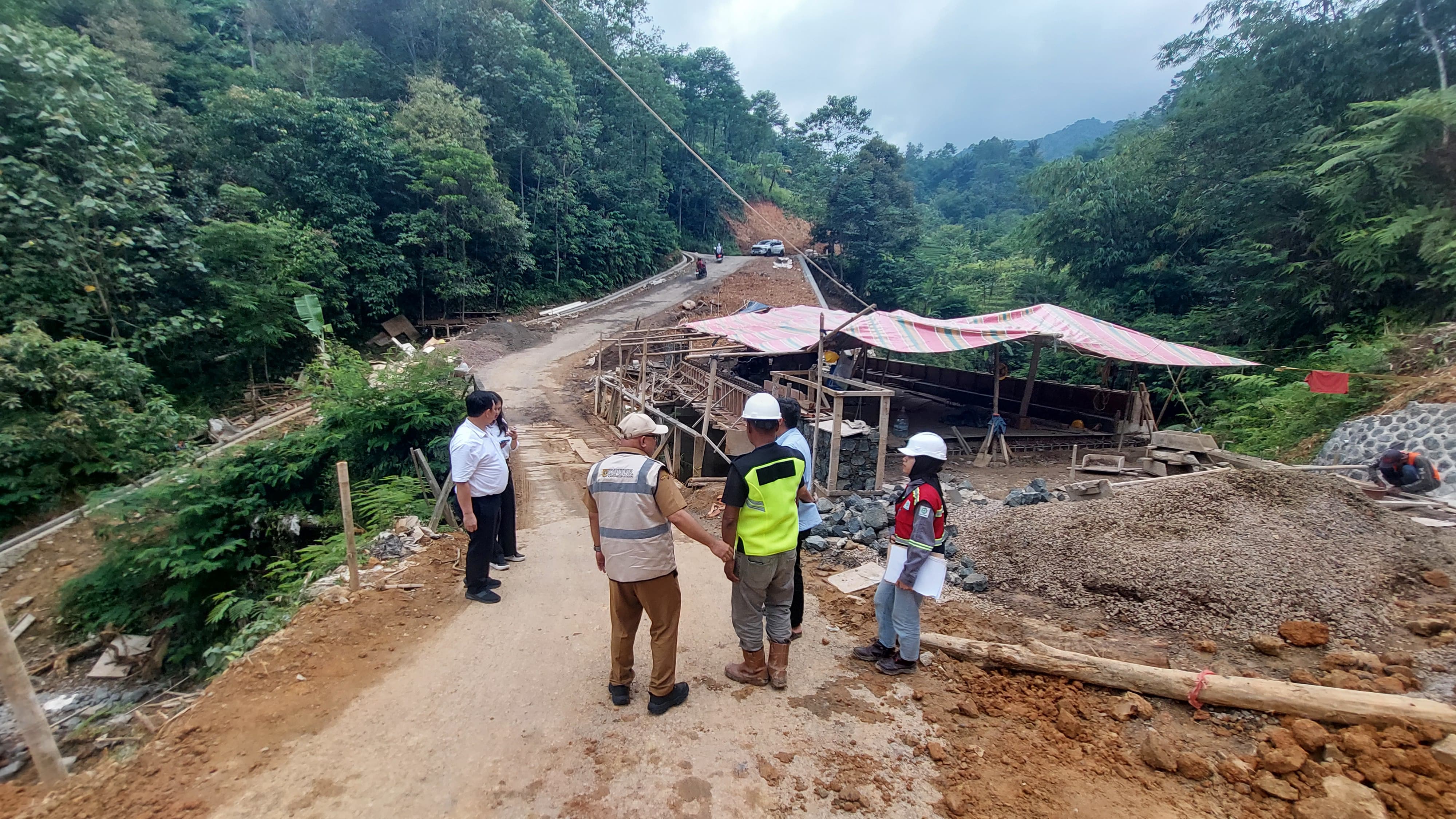 Petugas Dinas PUPR bersama pelaksana saat meninjau pembangunan Jembatan Ciparigi di Nanggung yang terdampak tebingan longsor.
