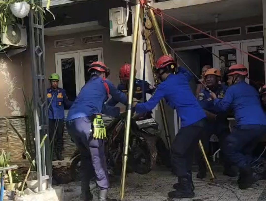 Petugas saat melakukan evakuasi motor dan sepeda masuk septic tank di Depok.