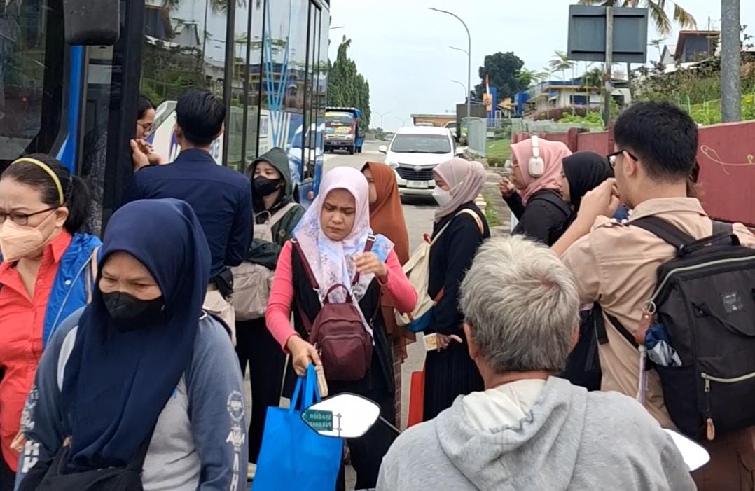 Penumpang TransJabodetabek P11 menumpuk di bahu jalan Pintu Tol Citeureup saat hendak naik bus tanpa adanya halte resmi, Selasa 9 Desember 2025.