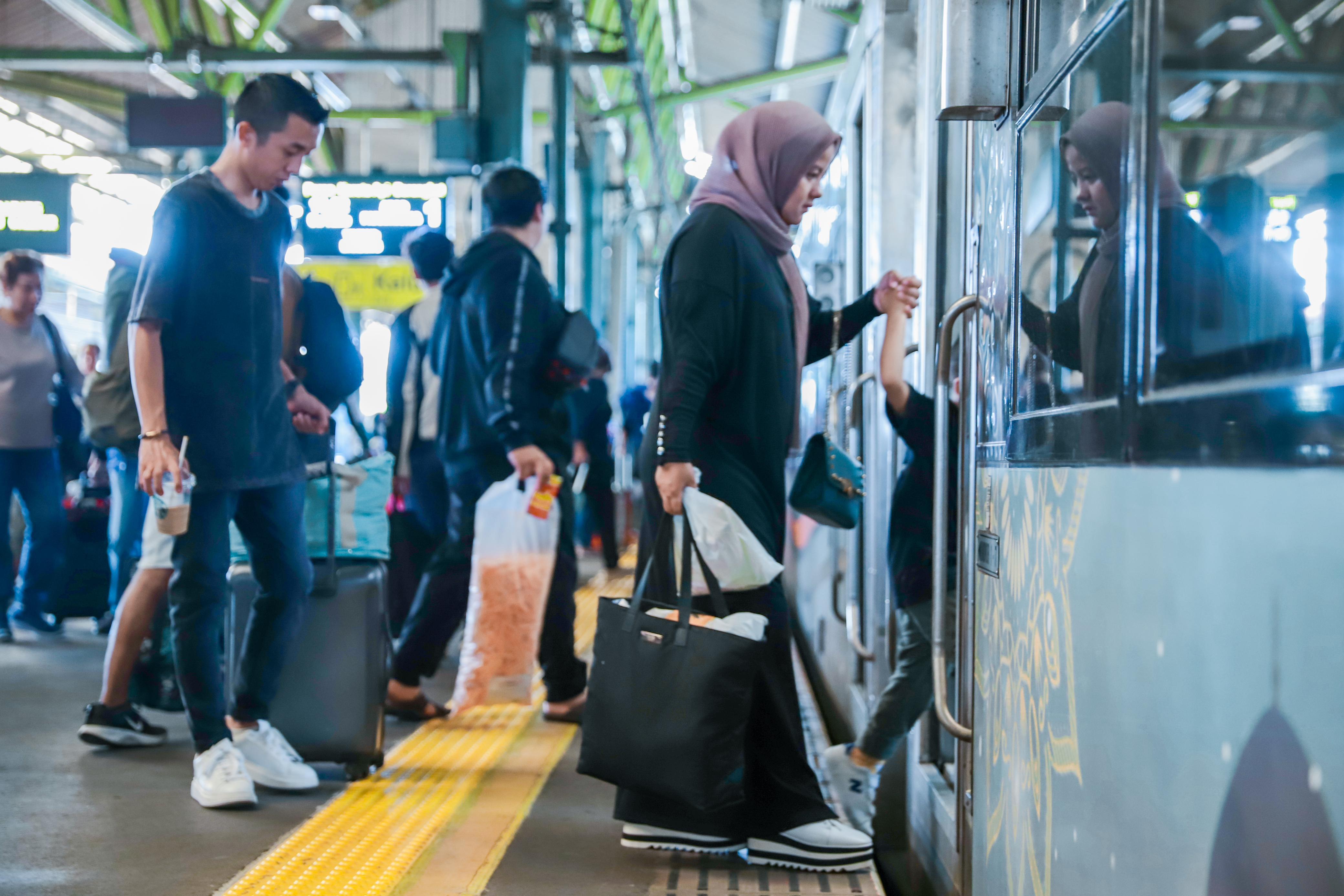 Penumpang kereta api hendak naik ke KA Jarak Jauh.