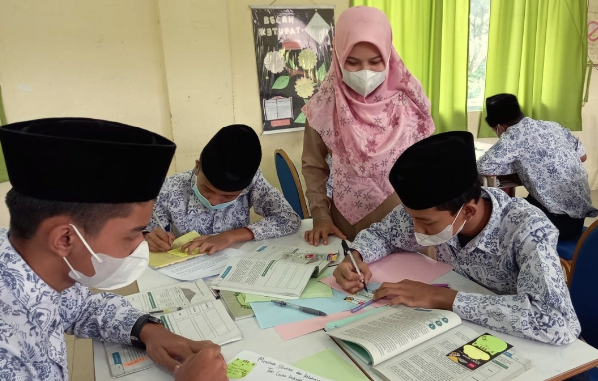 Guru membimbing siswa belajar di dalam kelas.