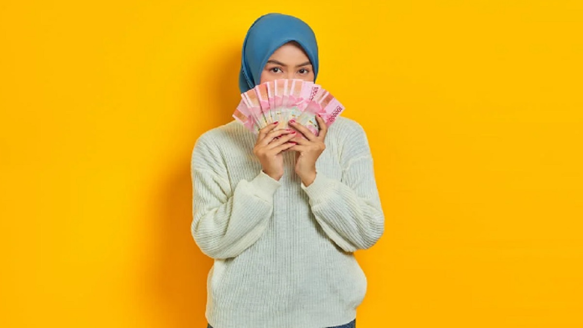 Ilustrasi seorang perempuan memegang uang pencairan bansos.