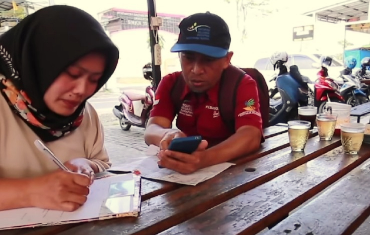 Pendamping sedang membantu KPM Bansos.
