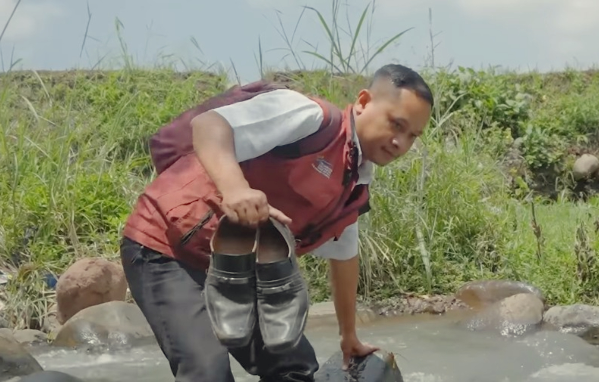 Petugas menyeberangi sungai untuk menemui KPM Bansos.