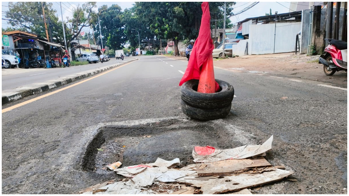 Lubang besar di tengah Jalan Raya Bogor yang bahayakan pengguna jalan.