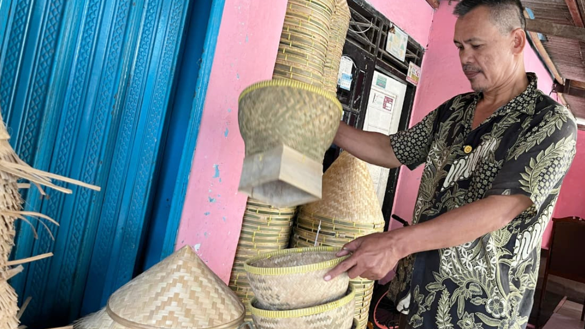 Sanang (57), pengepul kerajinan bambu di Desa Mampir, Kecamatan Cileungsi, Kabupaten Bogor, menyusun hasil anyaman bambu yang dikumpulkan dari para pengrajin sebelum dipasarkan ke luar daerah.