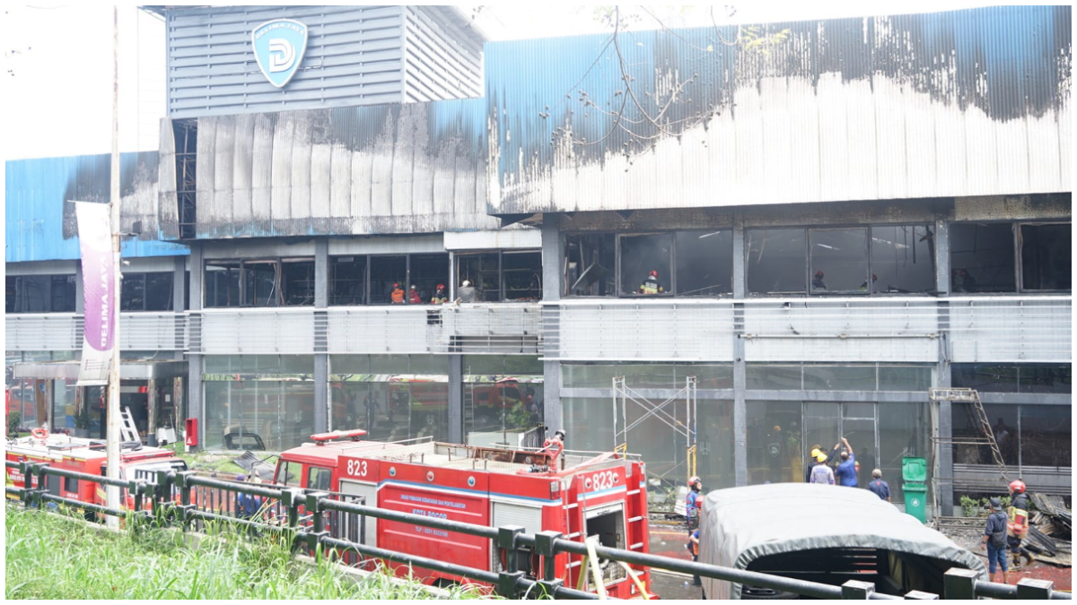Petugas Damkar melakukan pendinginan di gedung Karoseri Delima Jaya yang terbakar.