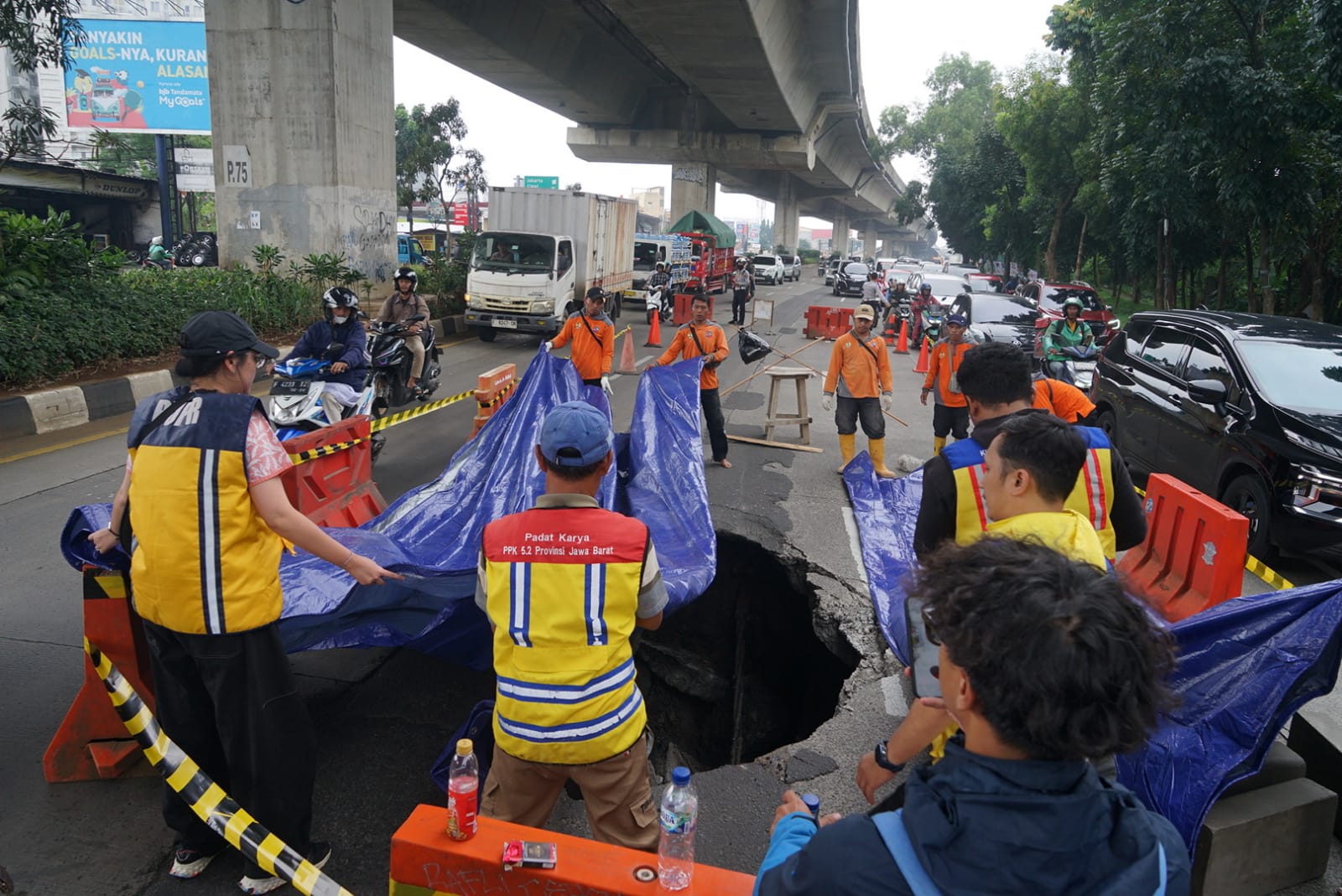 Petugas dari PPK 52 Provinsi Jawa Barat dan Kemen PUPR, berusaha menutupi lubang di Jalan Sholeh Iskandar, Kota Bogor, menggunakan terpal, Jumat 13 Februari 2026.