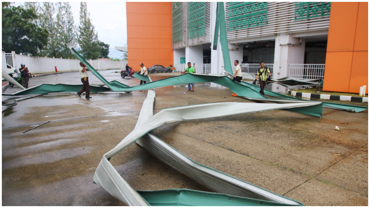 Petugas merapikan atap Stadion Pakansari yang roboh akibat angin dan hujan deras.