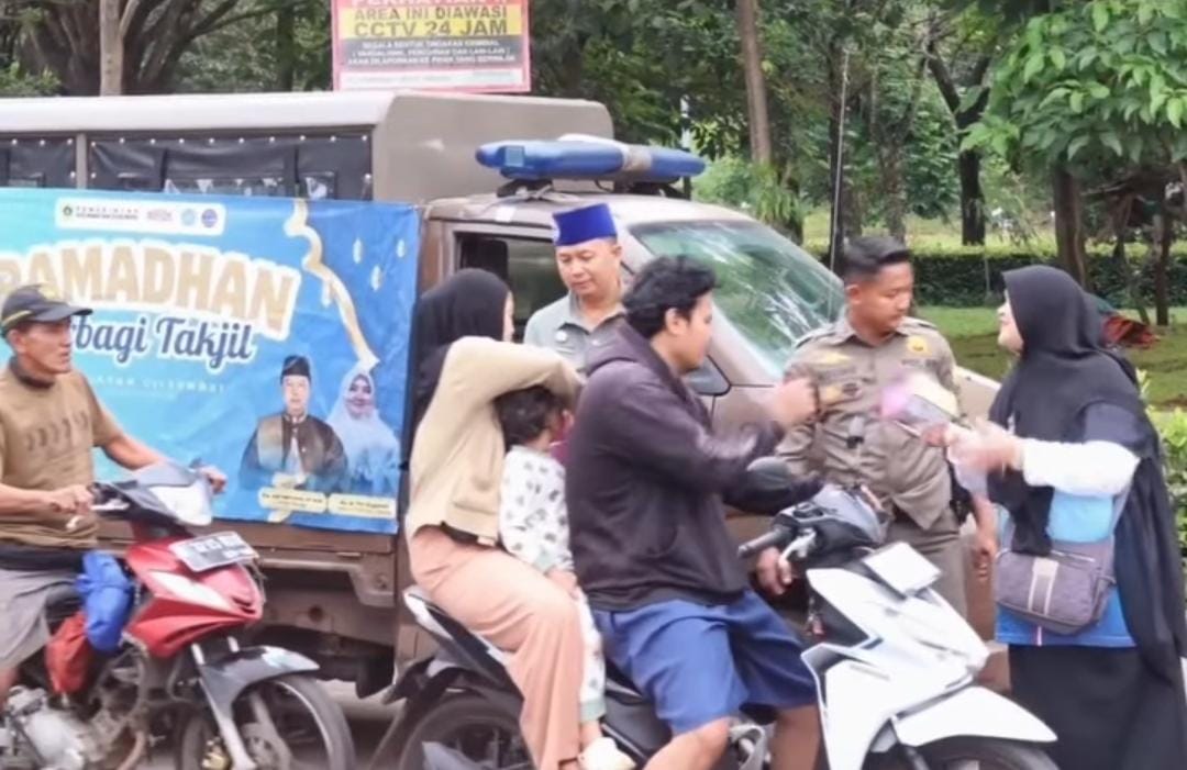 Camat Cileungsi, Adi Henryana (songkok biru) saat membagikan takjil kepada pengendara.