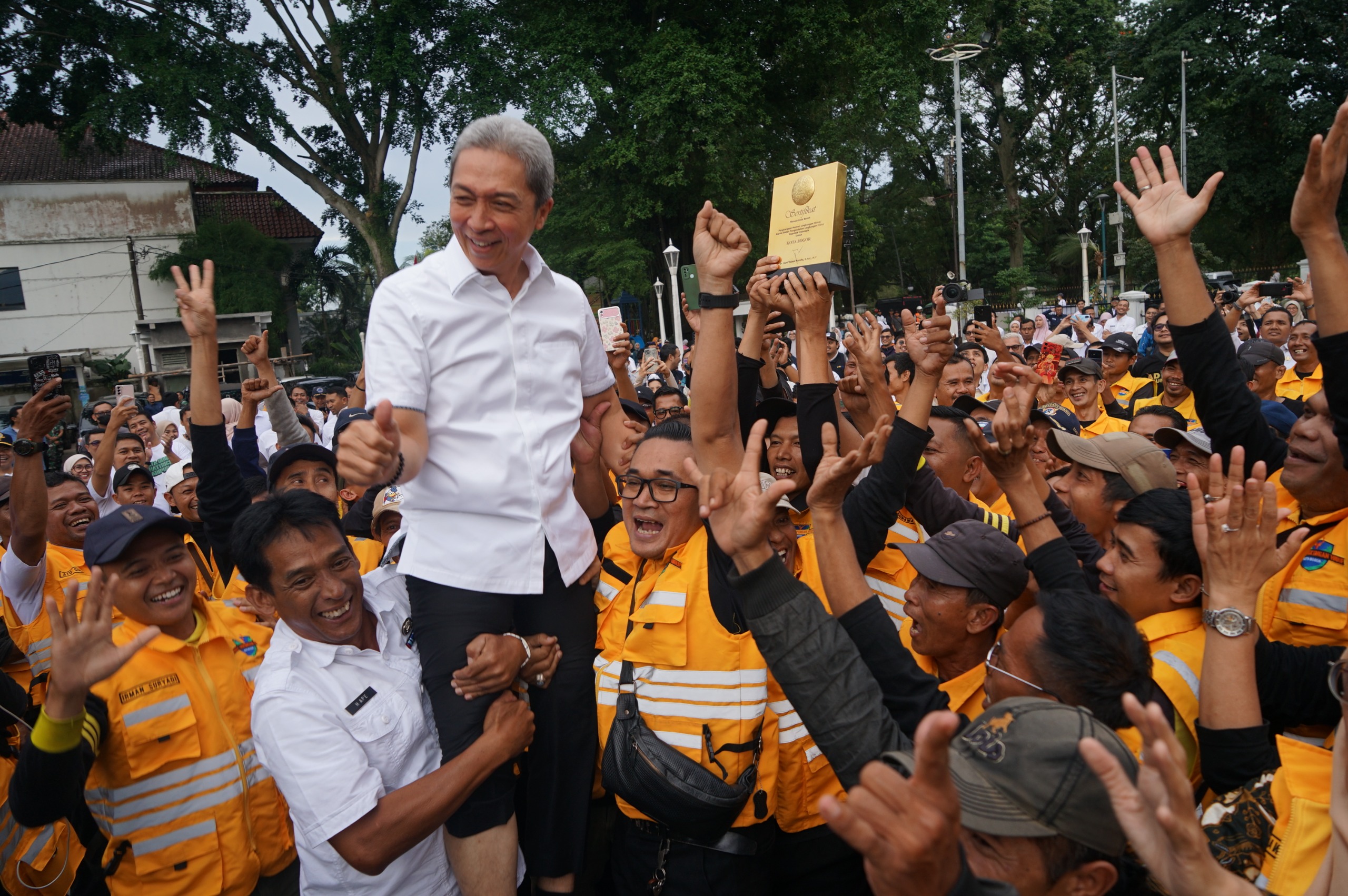 Wali Kota Bogor, Dedie A Rachim bersama Kadis DLH Kota Bogor, Deni wismanto dan pasukan kuning mengangkat tropy penghargaan bogor menuju kota bersih.
